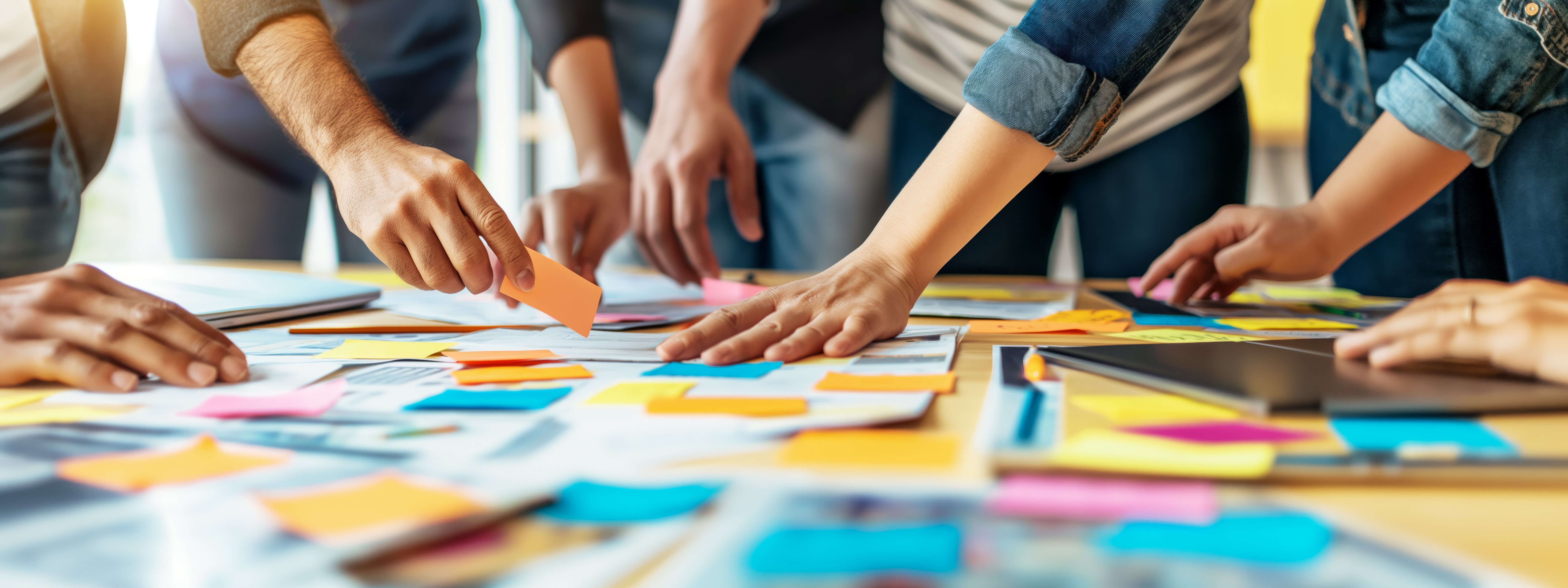 Hands touching and grabbing colorful sticky notes on a table top.